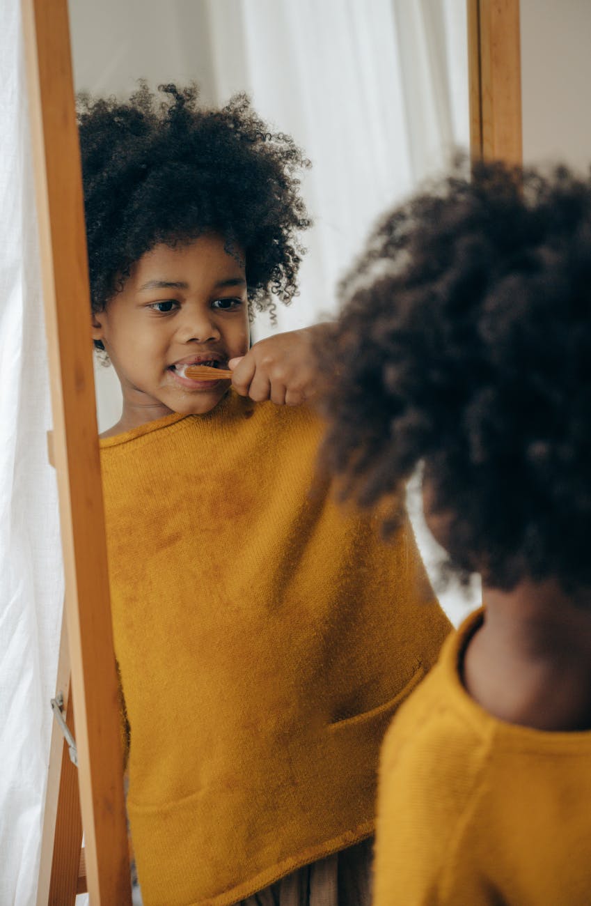 Toddler brushing teeth while looking in the mirror – teaching kids healthy oral care habits.