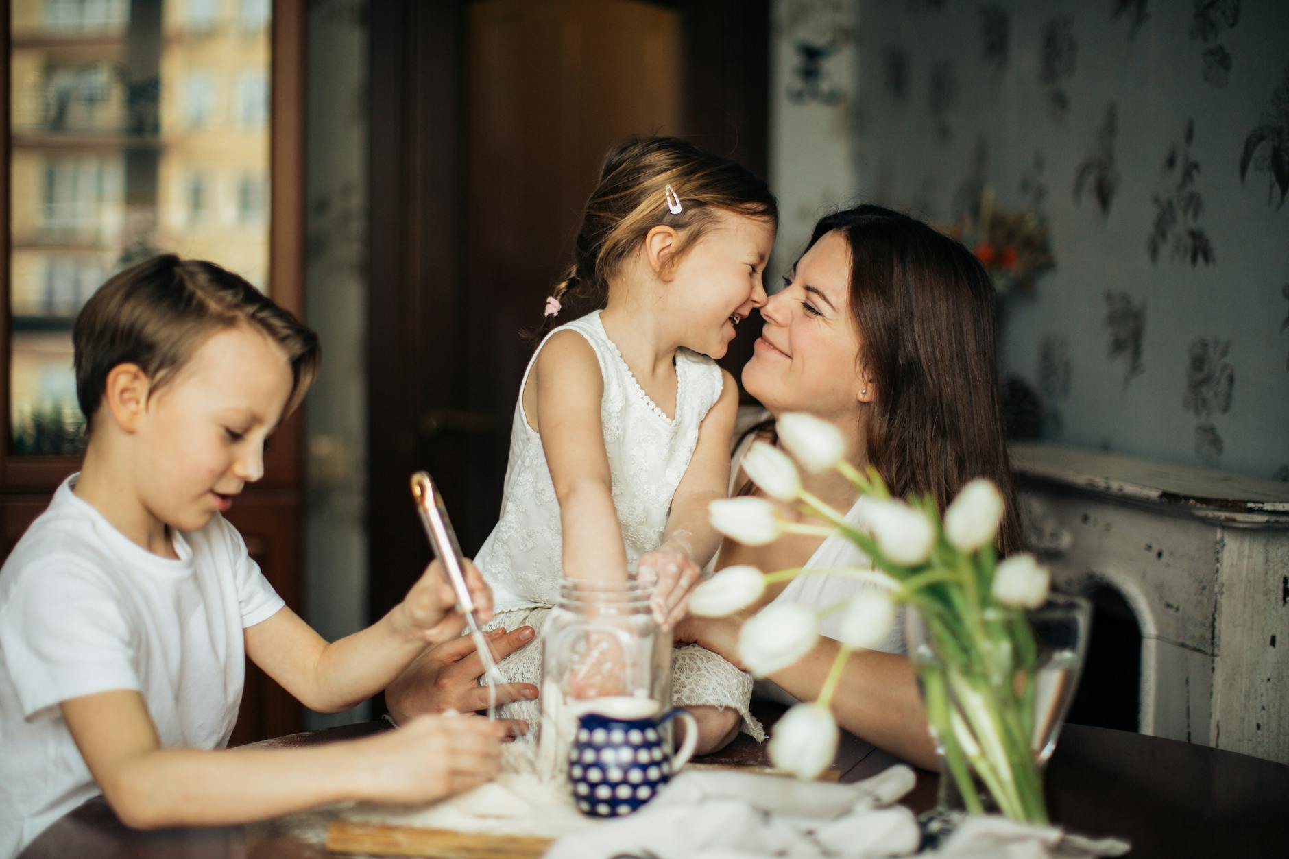 Mother calmly interacting with her children at the table, illustrating respectful parenting and understanding child behavior