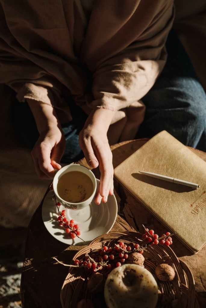 Mom’s hand holding a coffee mug beside a journal, representing mental load offloading and emotional relief for overwhelmed mothers