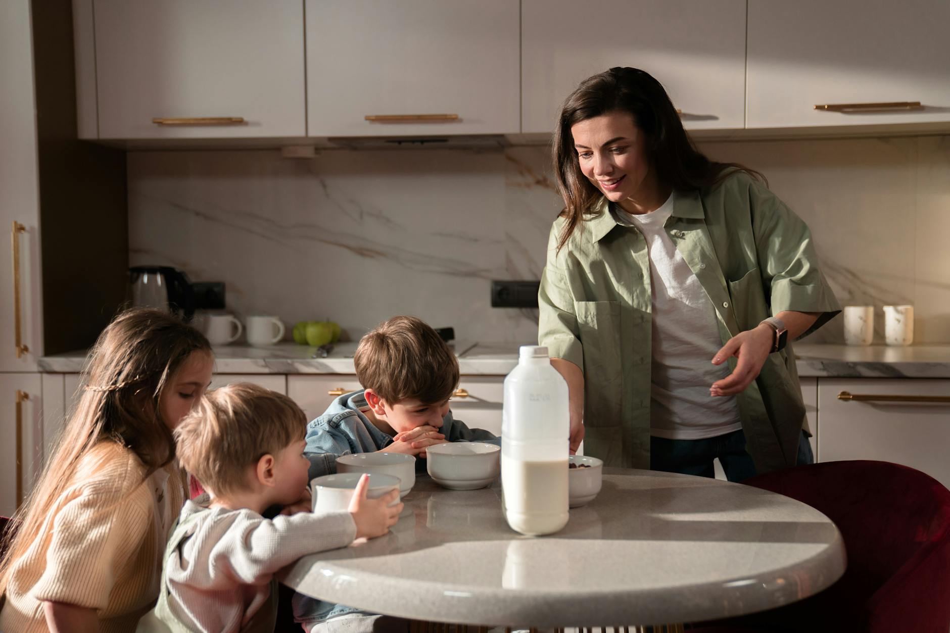 A mother serves food to her two young sons sitting at the dining table, highlighting the importance of regular meals in preventing toddler temper tantrums.