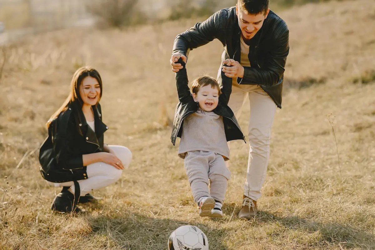 Father and mother playing ball with young son - parents modelling positive behavior at home